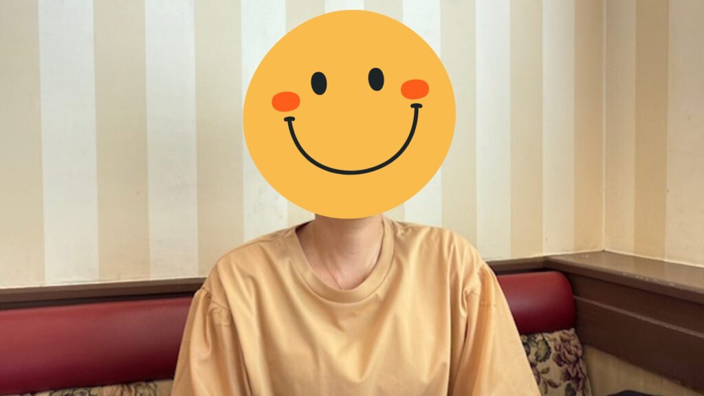 42組の内覧を経て高値成約を果たした売主さまのインタビュー写真。顔はスマイルマークで隠している。