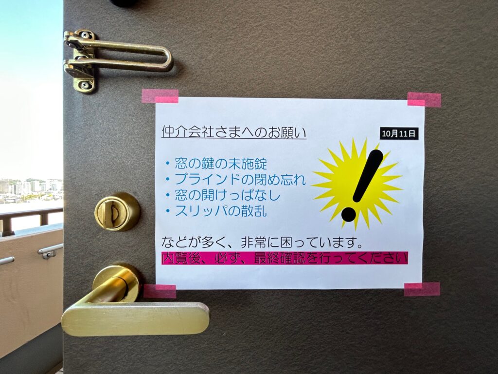 玄関扉に貼られた仲介会社向けの注意書き。窓の鍵の未施錠・ブラインドの閉め忘れ・窓の開けっぱなし・スリッパの散乱について、内覧後の最終確認を求める内容が記載されている